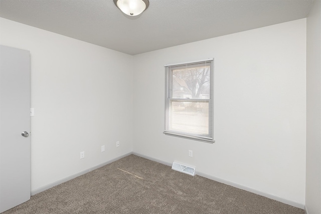 carpeted empty room with visible vents, baseboards, and a textured ceiling