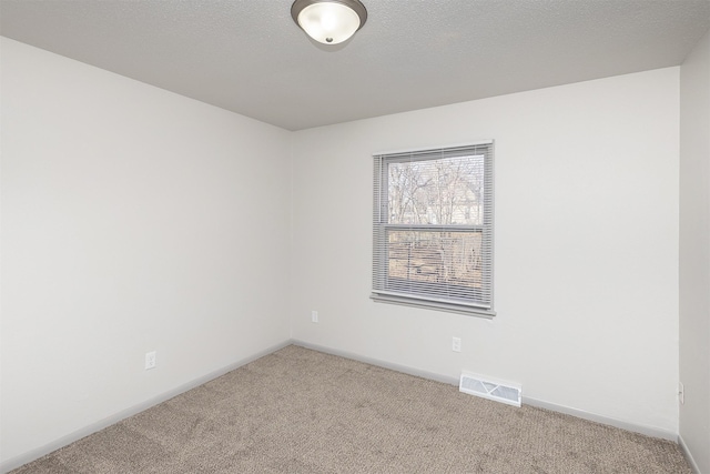 unfurnished room featuring visible vents, baseboards, carpet, and a textured ceiling