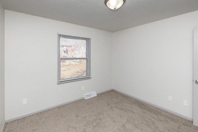 carpeted spare room featuring visible vents, baseboards, and a textured ceiling