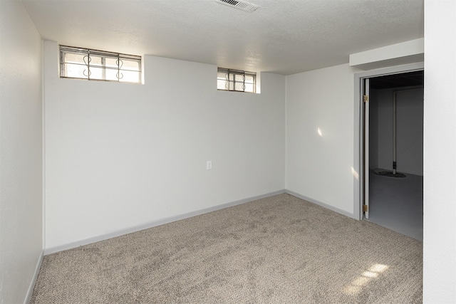 basement with baseboards, visible vents, a textured ceiling, and carpet