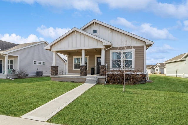 view of front of house featuring cooling unit, covered porch, board and batten siding, and a front lawn