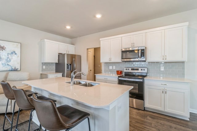 kitchen with a sink, stainless steel appliances, a breakfast bar, and an island with sink