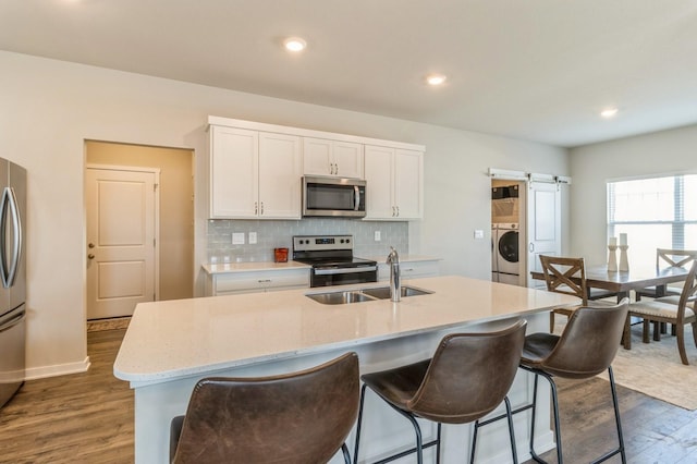 kitchen with backsplash, a barn door, washer / dryer, stainless steel appliances, and a sink