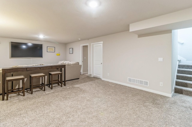 carpeted living area with visible vents, baseboards, and stairs