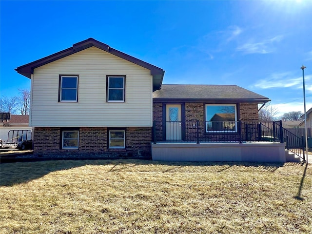 rear view of house featuring a yard and brick siding