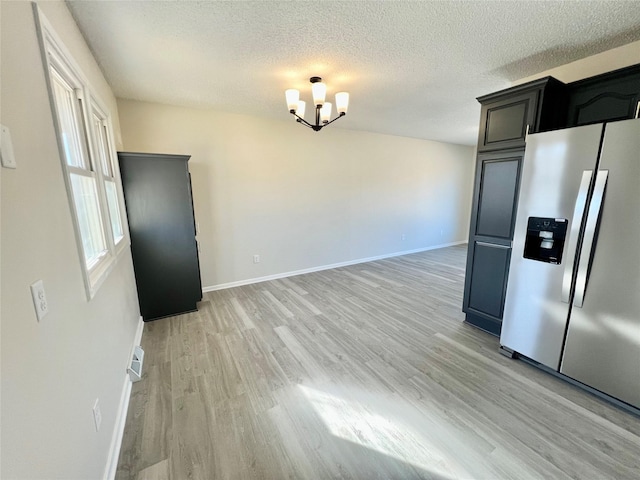 interior space featuring a textured ceiling, light wood-type flooring, and baseboards