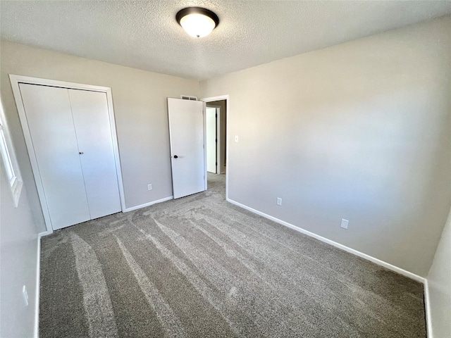 unfurnished bedroom featuring a closet, carpet flooring, a textured ceiling, and baseboards