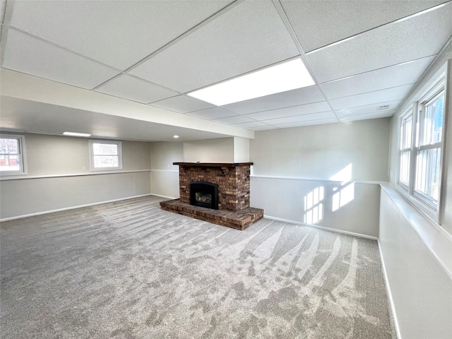 unfurnished living room featuring a paneled ceiling, baseboards, carpet, and a brick fireplace