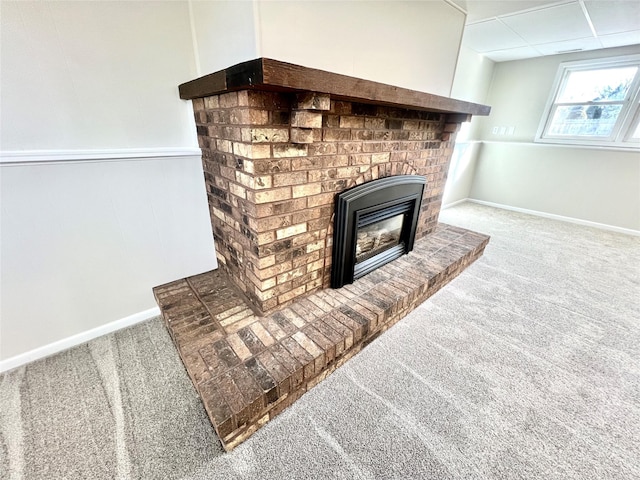 interior details with a brick fireplace, baseboards, a paneled ceiling, and carpet