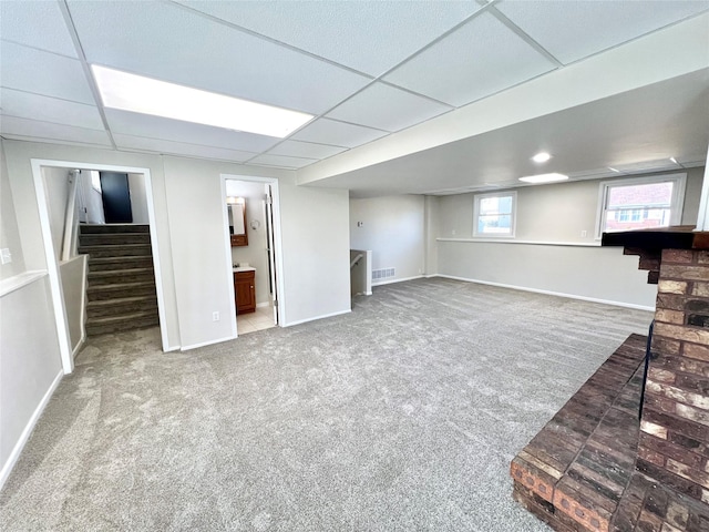 basement featuring a drop ceiling, visible vents, carpet floors, and stairs