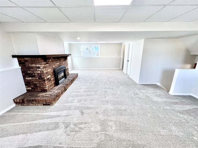 unfurnished living room with a fireplace, carpet, baseboards, and a drop ceiling