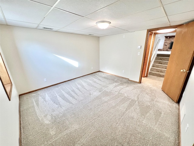 finished basement featuring visible vents, baseboards, a drop ceiling, stairway, and carpet floors