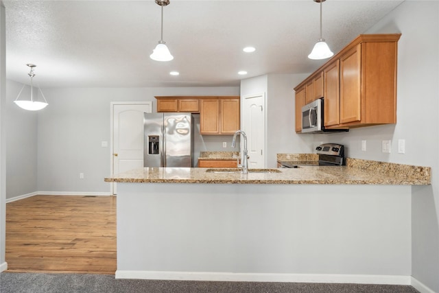 kitchen featuring pendant lighting, a sink, appliances with stainless steel finishes, a peninsula, and light stone countertops