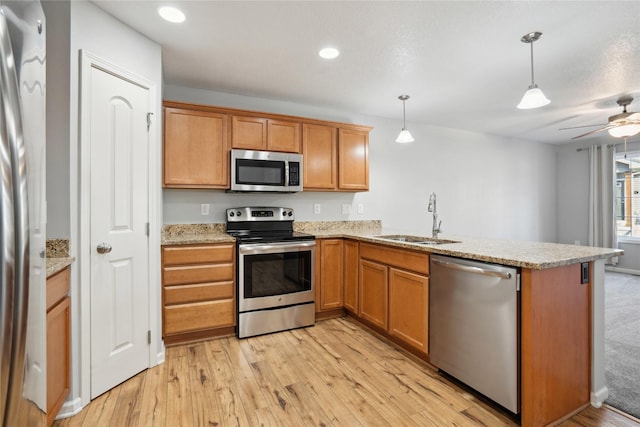 kitchen featuring a peninsula, light wood-style flooring, appliances with stainless steel finishes, and a sink