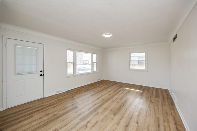 unfurnished room featuring baseboards, visible vents, and light wood-type flooring