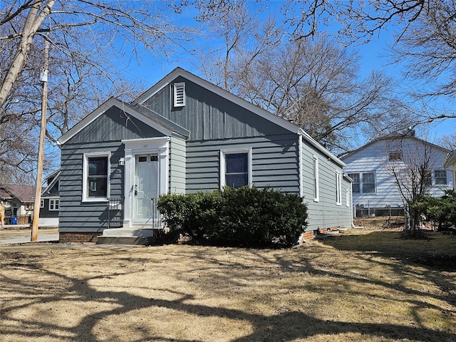 bungalow with board and batten siding and a front lawn