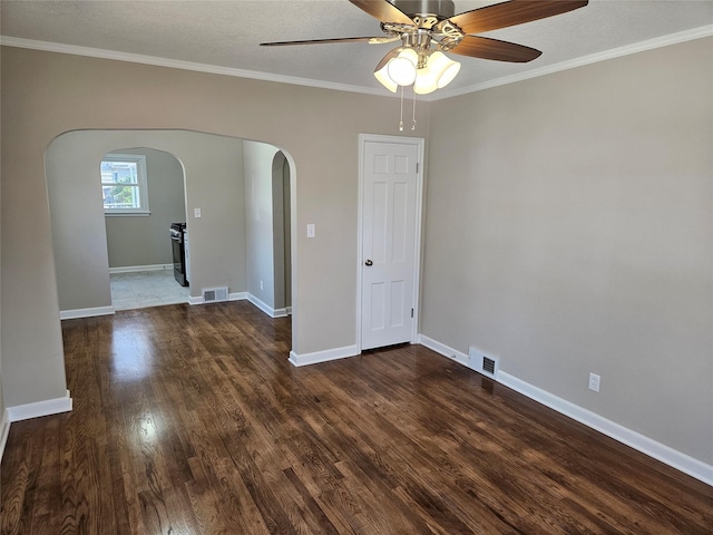 spare room featuring dark wood finished floors, arched walkways, visible vents, and baseboards