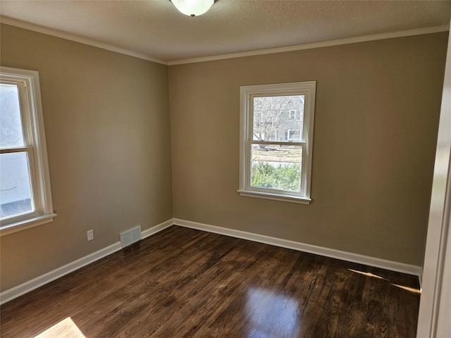 empty room with crown molding, dark wood-style floors, visible vents, and baseboards