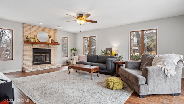 living area featuring plenty of natural light, a brick fireplace, and wood finished floors