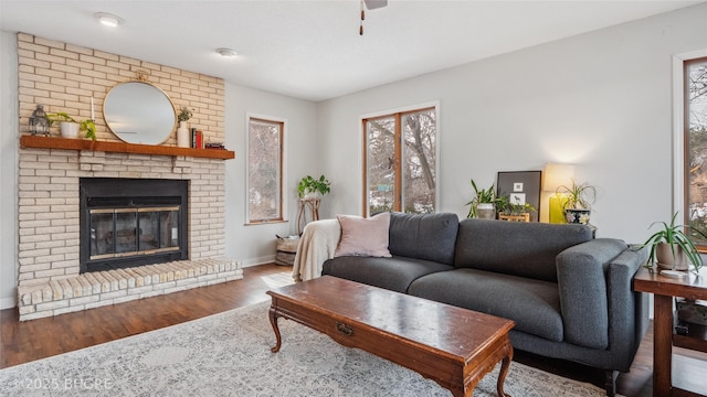 living area with wood finished floors, a fireplace, baseboards, and ceiling fan