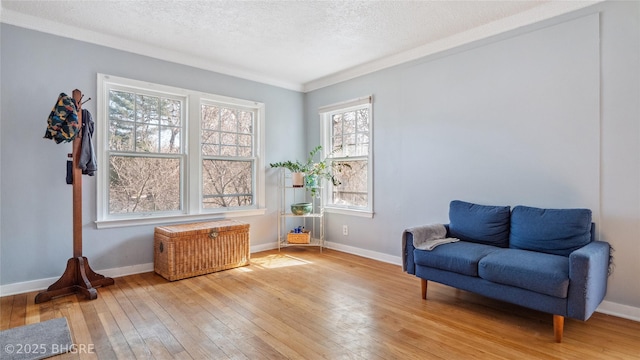 sitting room with baseboards, a textured ceiling, light wood-style flooring, and crown molding