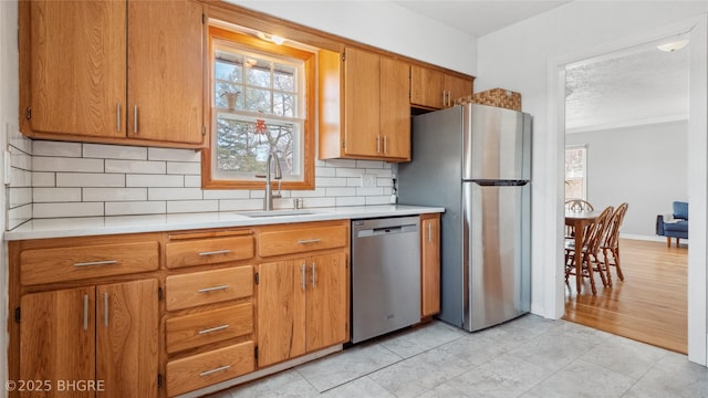 kitchen featuring a sink, decorative backsplash, appliances with stainless steel finishes, and light countertops