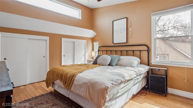 bedroom with wood finished floors, multiple closets, and baseboards