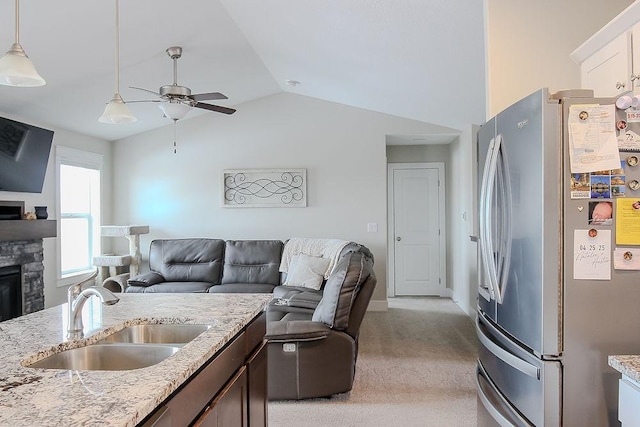 kitchen featuring a fireplace, freestanding refrigerator, a sink, vaulted ceiling, and open floor plan