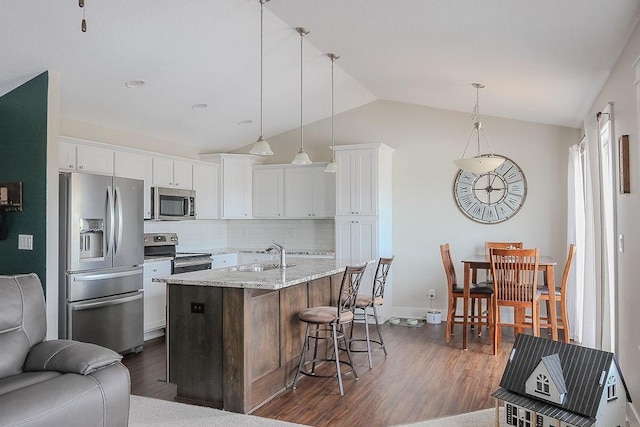 kitchen with dark wood-style flooring, a sink, vaulted ceiling, white cabinets, and appliances with stainless steel finishes