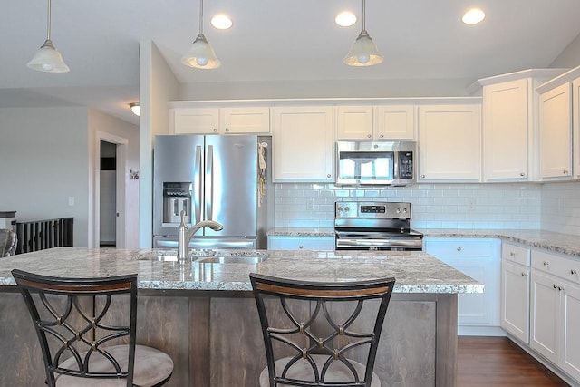 kitchen with backsplash, appliances with stainless steel finishes, white cabinetry, and pendant lighting