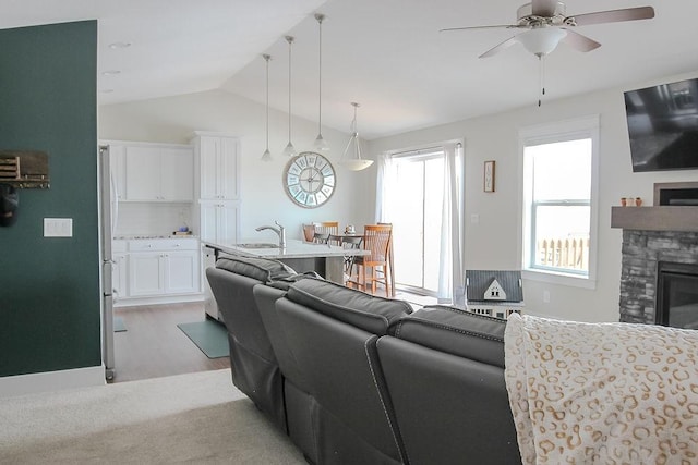 living area with a fireplace, a ceiling fan, and vaulted ceiling