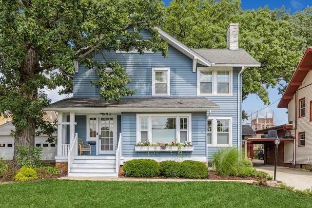 view of front of property with a front yard, covered porch, and a chimney