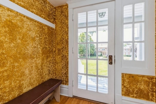 doorway with wallpapered walls and wood finished floors