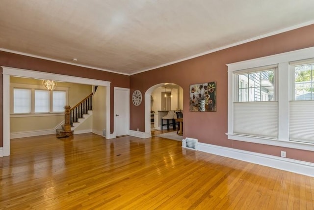 unfurnished living room with light wood-style flooring, stairs, baseboards, and ornamental molding