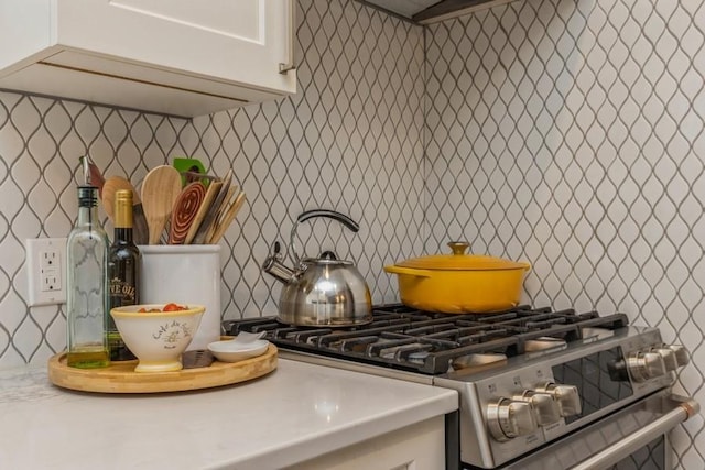 room details with white cabinetry, gas range, light countertops, and tasteful backsplash