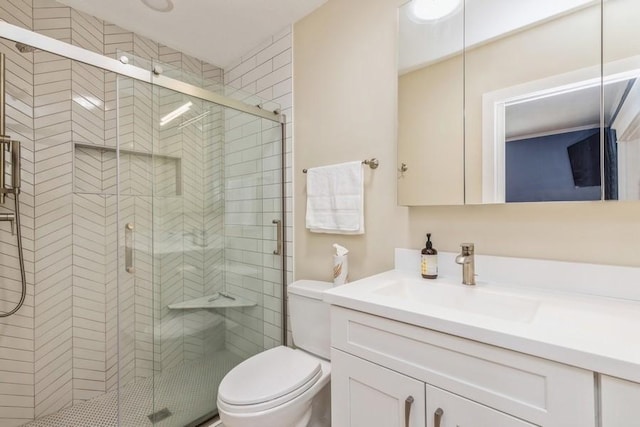 bathroom with vanity, a shower stall, and toilet