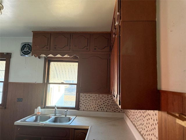 kitchen featuring wainscoting, light countertops, wood walls, and a sink