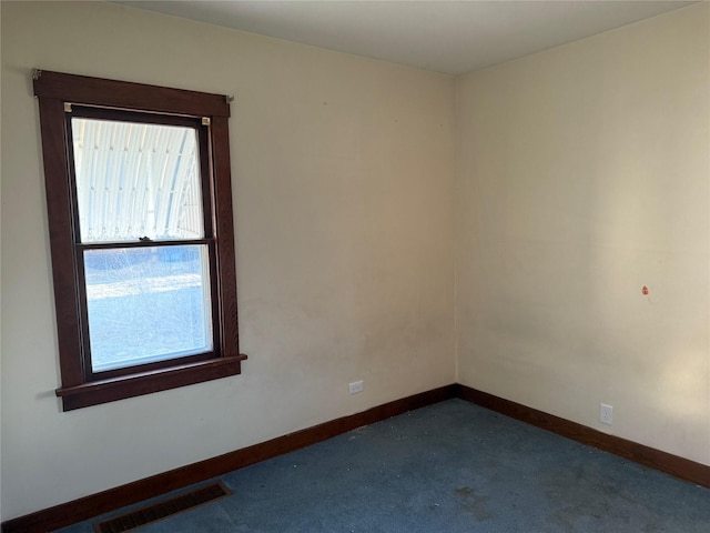 empty room featuring baseboards, visible vents, and dark colored carpet