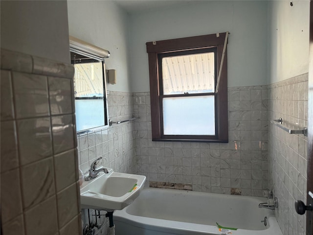 full bath with tile walls and a sink