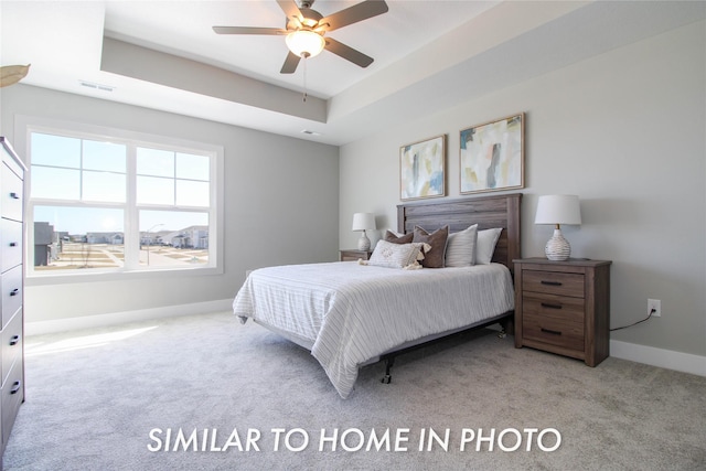 carpeted bedroom featuring baseboards, a raised ceiling, visible vents, and ceiling fan