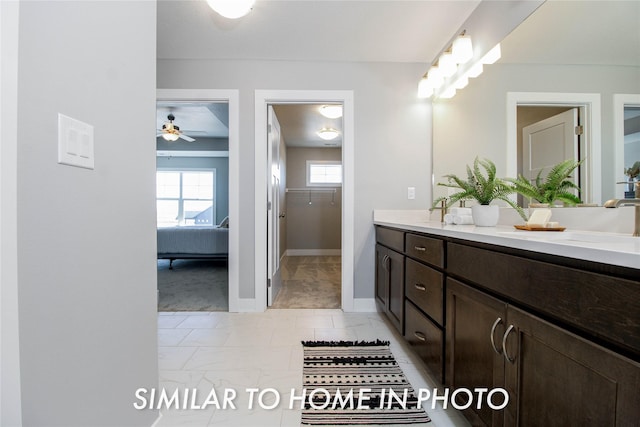 bathroom featuring a ceiling fan, a sink, connected bathroom, double vanity, and baseboards