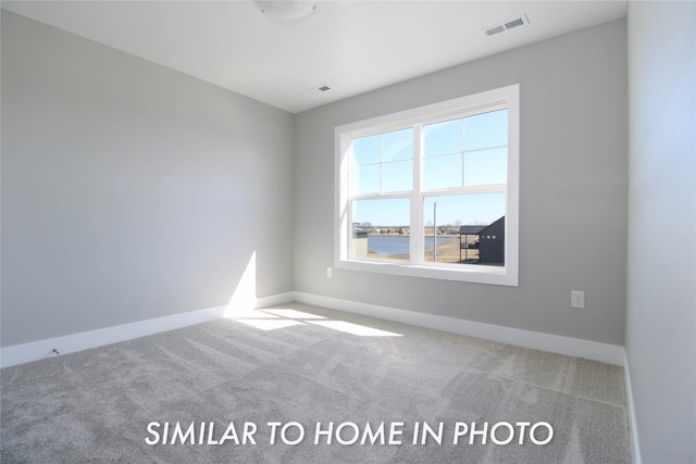 carpeted spare room featuring visible vents and baseboards