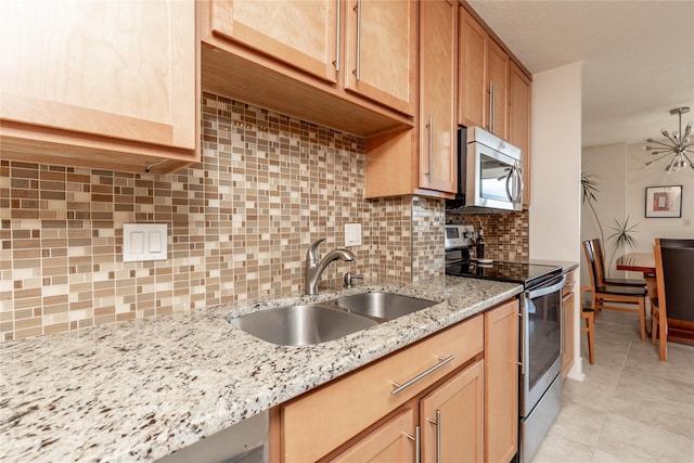 kitchen featuring tasteful backsplash, light tile patterned floors, light stone counters, appliances with stainless steel finishes, and a sink