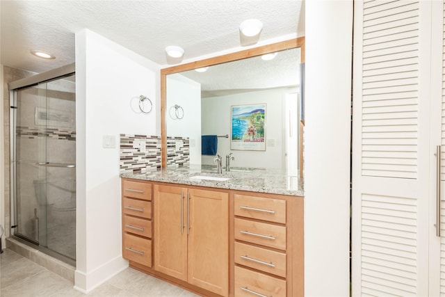 bathroom featuring decorative backsplash, a stall shower, and a textured ceiling