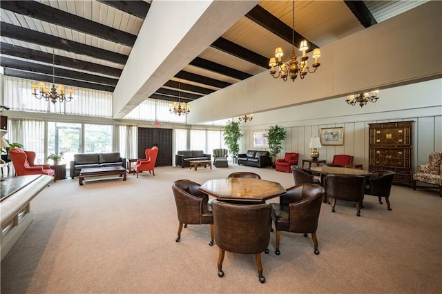 dining room with beam ceiling, a decorative wall, a notable chandelier, and carpet floors