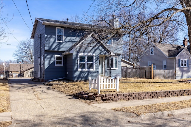 colonial inspired home with fence, driveway, and a chimney