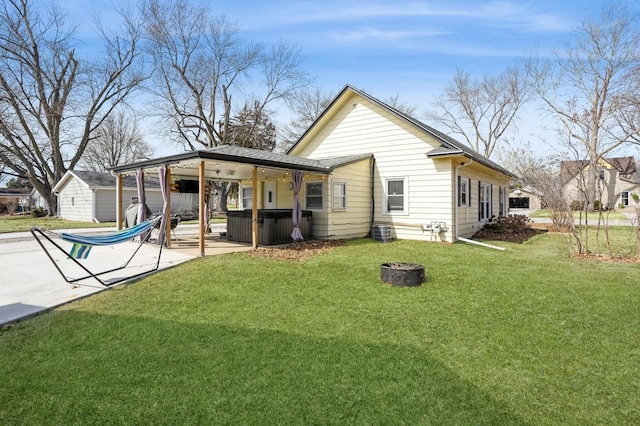 back of property featuring a patio area, a lawn, and a hot tub