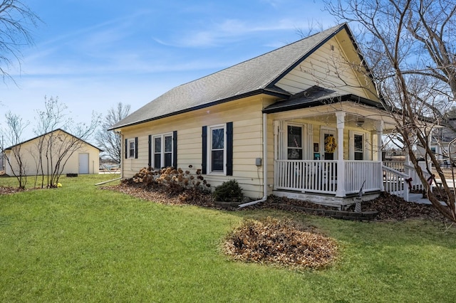 view of side of home featuring a yard, roof with shingles, and a porch