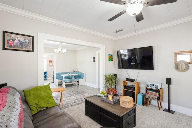 carpeted living room featuring ceiling fan with notable chandelier, crown molding, baseboards, and visible vents