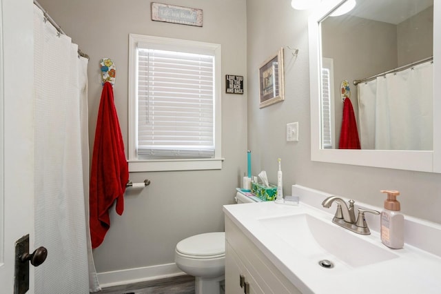 full bathroom with vanity, toilet, baseboards, and plenty of natural light